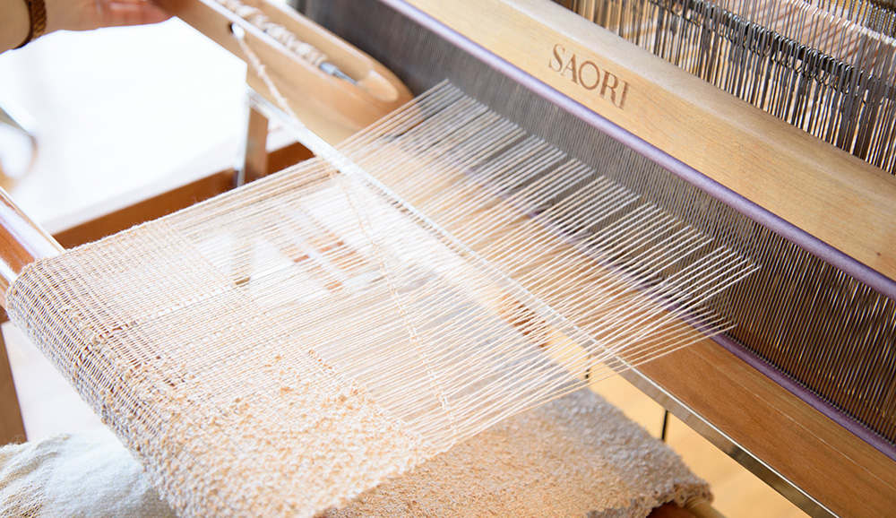 織り縮みしないように、ヨコ糸が斜めに入りゆとりがある状態の時に、ペダルを踏み替えて織ります。